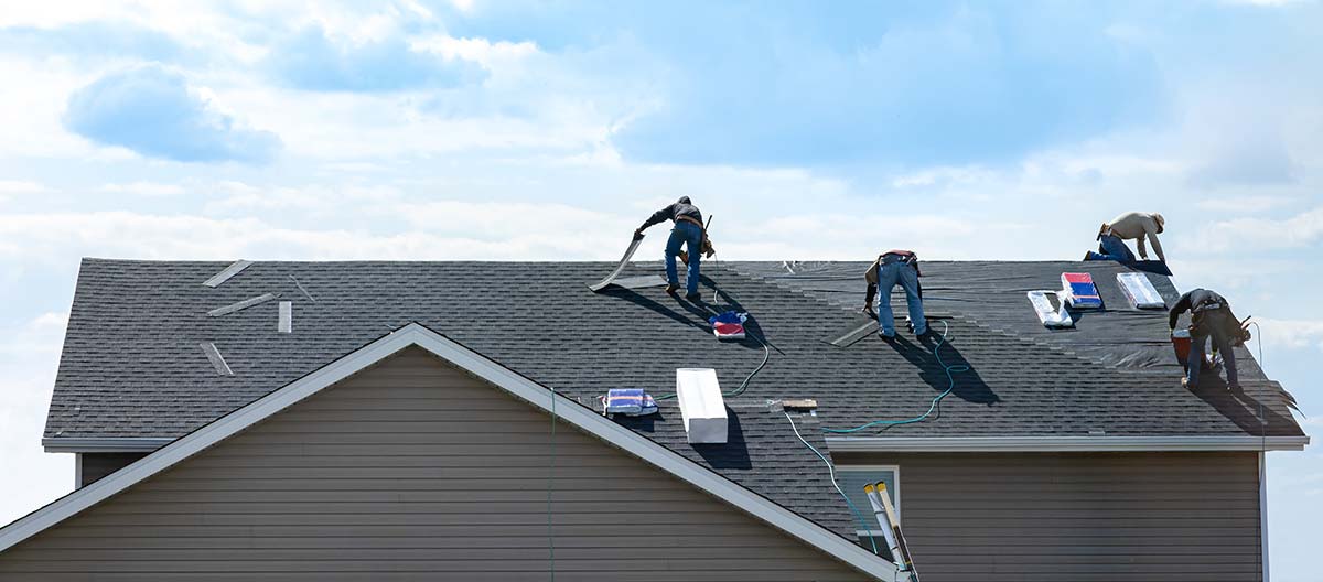 dumpsters-for-roofing roofers tearing shingles off a roof
